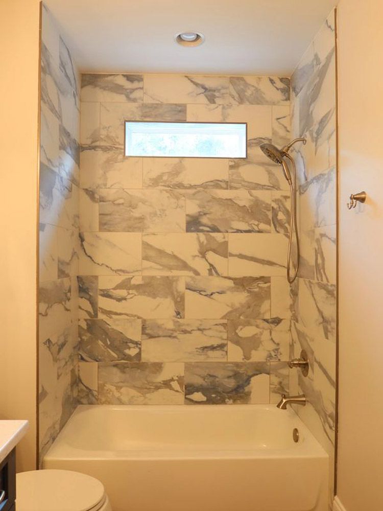 A bathroom with a tub , toilet and shower.