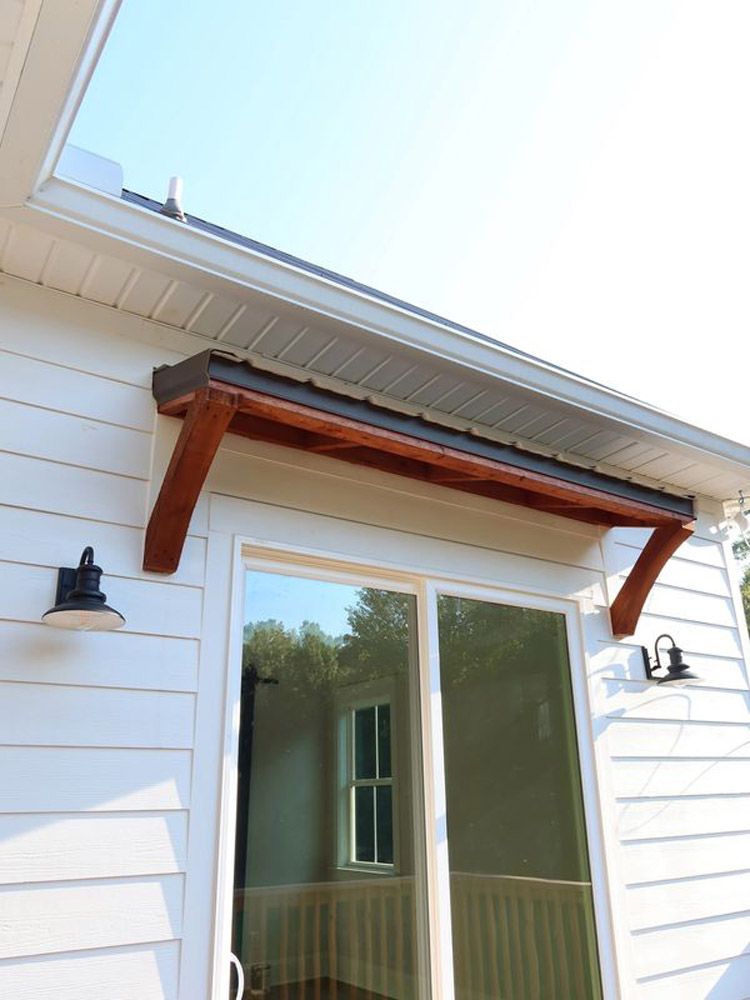 A white house with a wooden awning over a sliding glass door