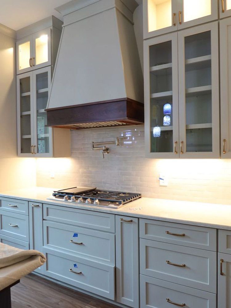 A kitchen with white cabinets and a stove top oven.