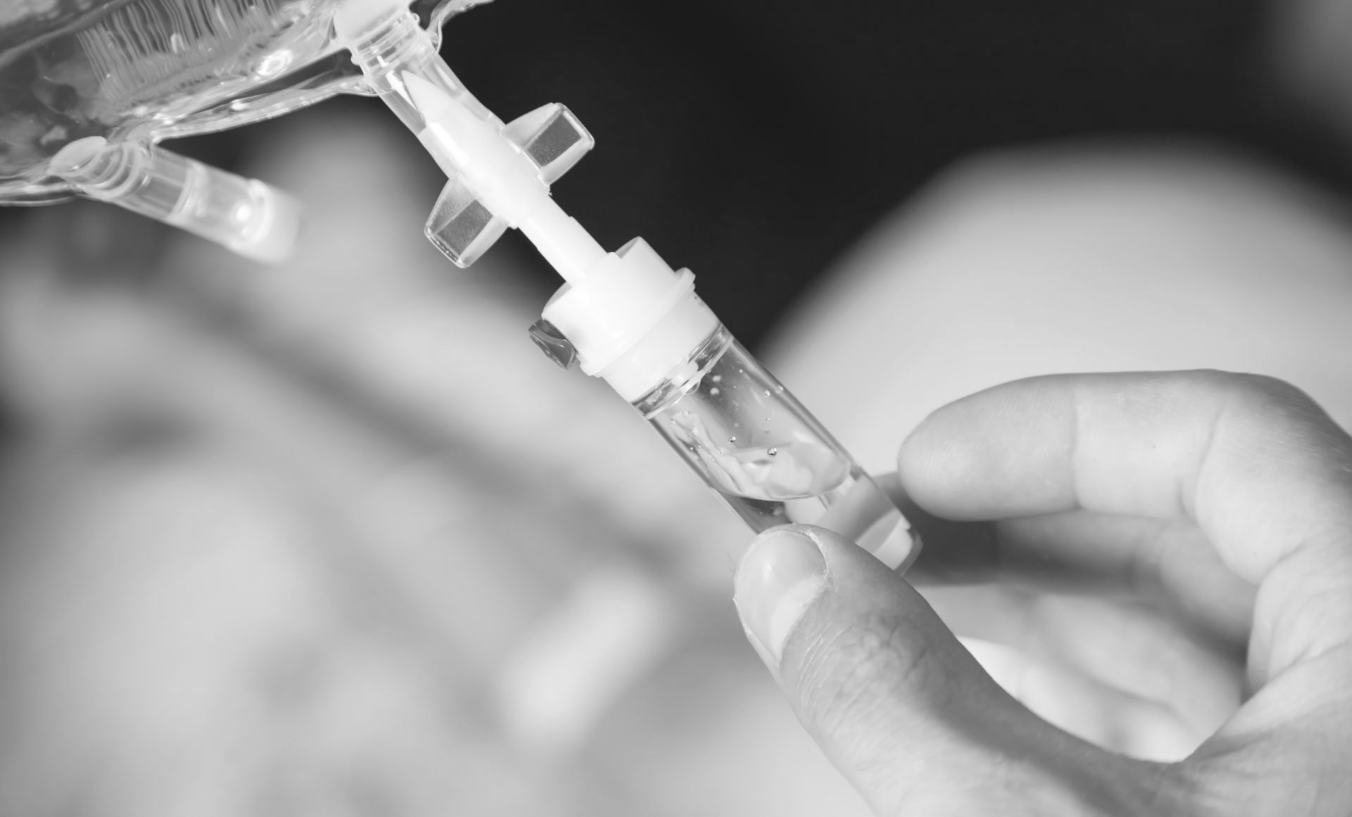 A person is holding a syringe with a drop of liquid in it.