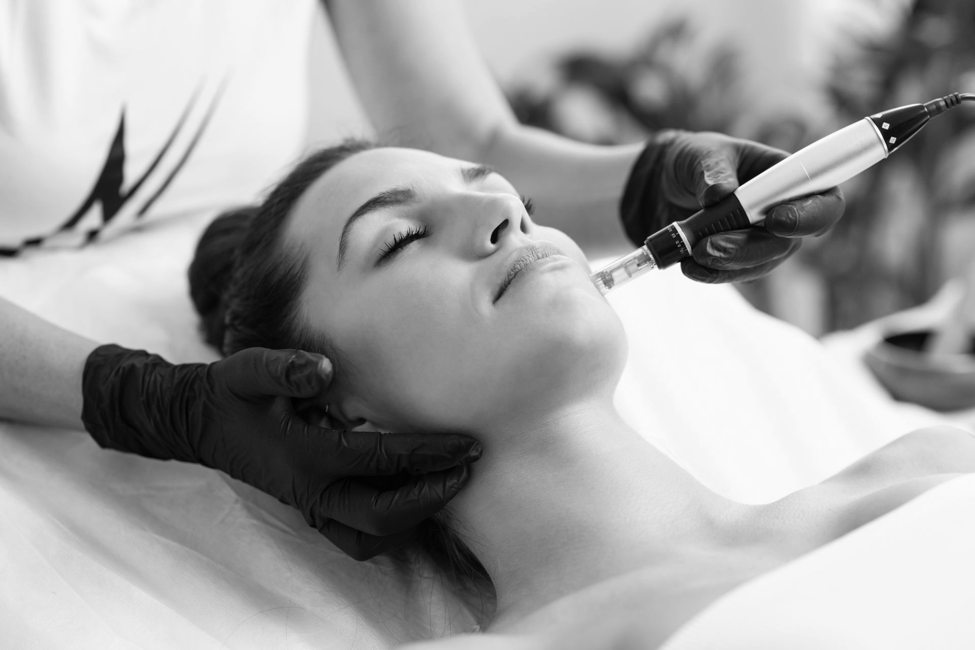 A woman is getting a facial treatment in a black and white photo.