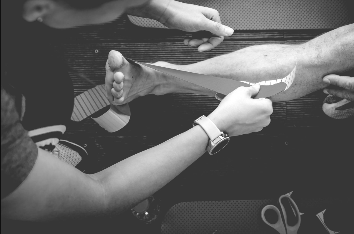 A black and white photo of a person shaving another person 's leg