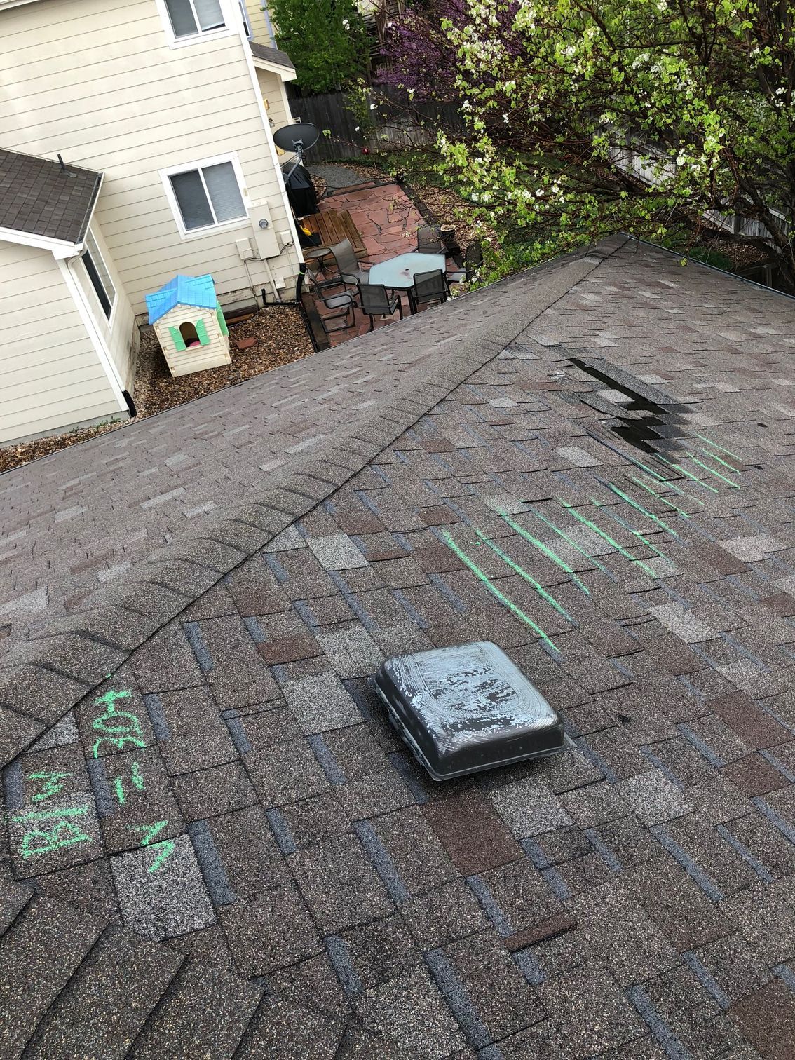 A residential roof showing chalk markings and a square vent, indicating an inspection or pending repair.