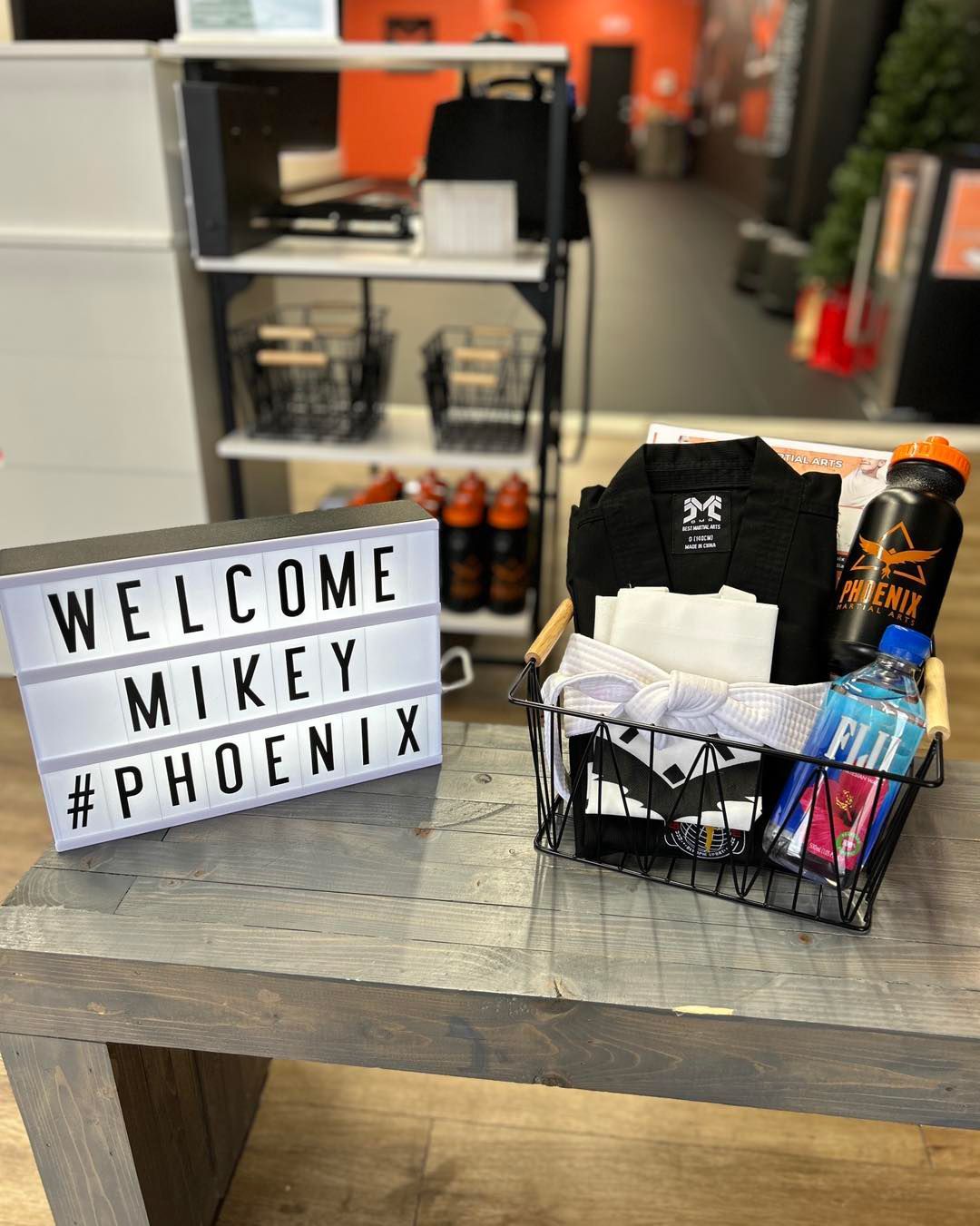 A welcome sign is sitting on a table next to a basket of clothes.