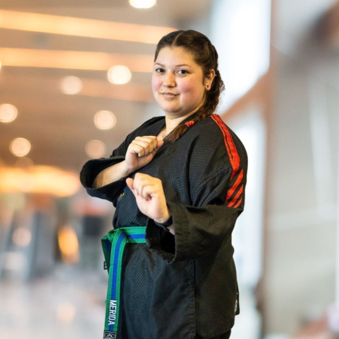 A woman wearing a black karate uniform with a green belt