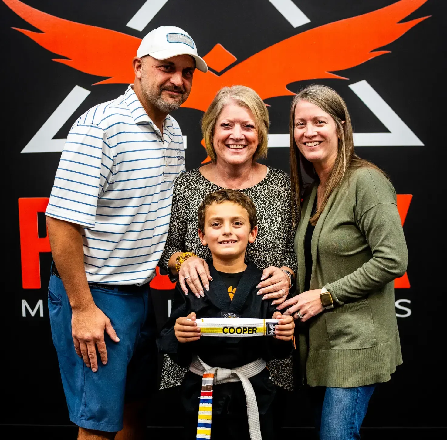 A kid receiving his martial arts belt with a happy family