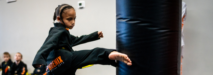 Phoenix Martial Arts student demonstrating focus and power during Taekwondo training in Murfreesboro. Child practicing a Taekwondo kick at Phoenix Martial Arts in Murfreesboro, TN, during class training.