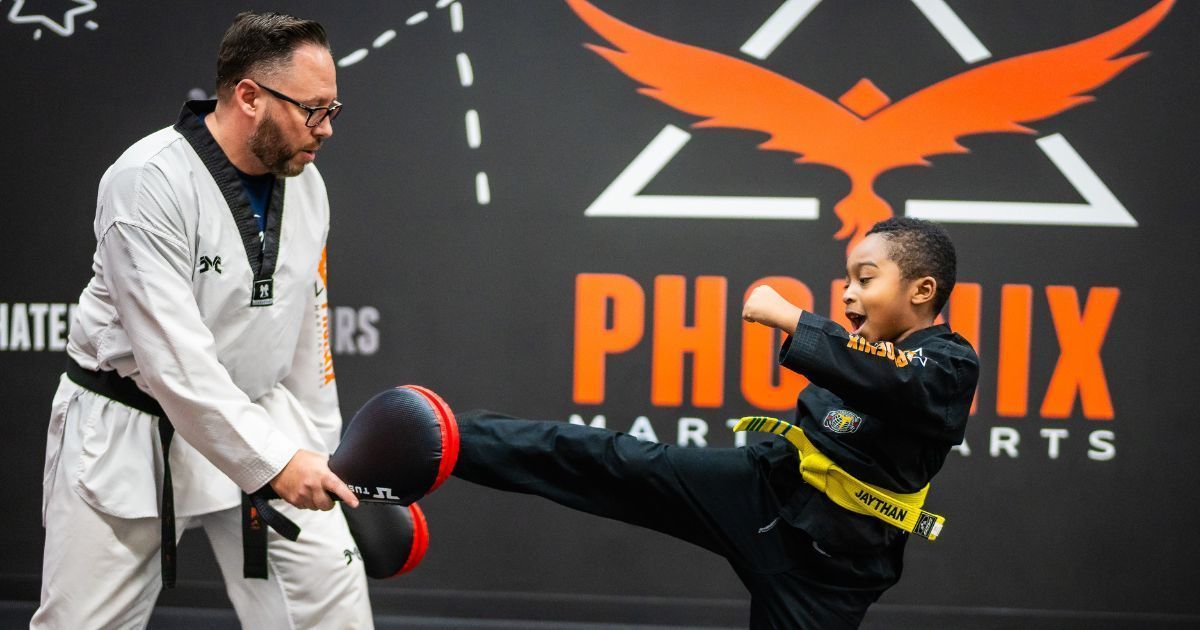 a man is teaching a young boy how to kick a kick pad .