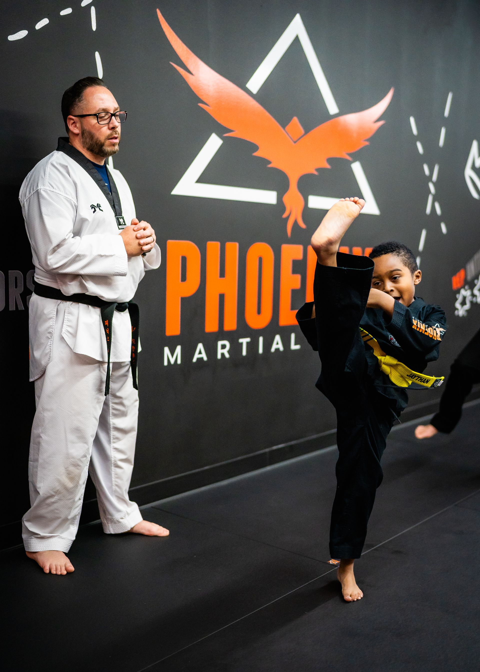 A man and a boy are practicing martial arts in a gym.