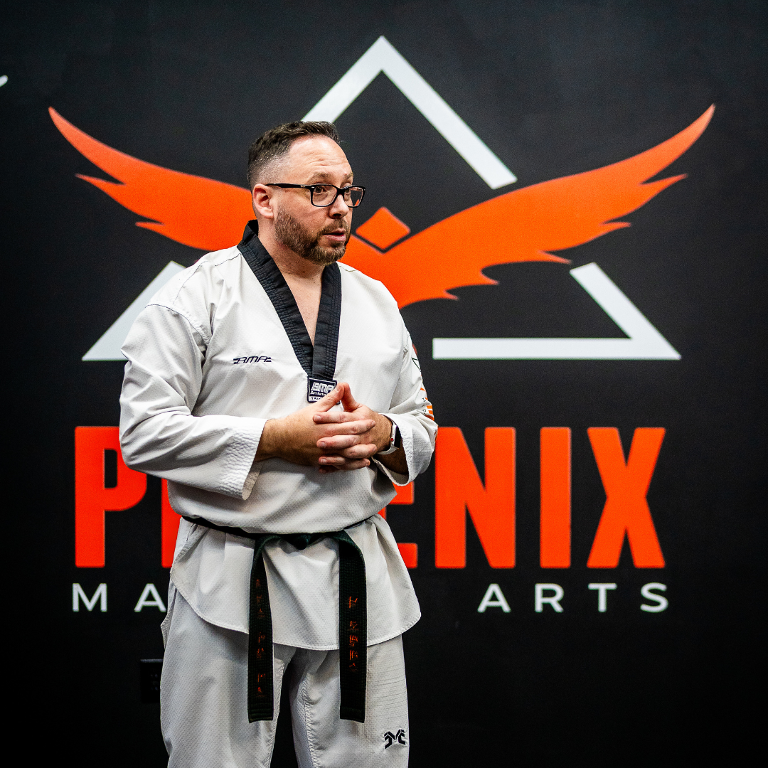 A group of children are practicing karate with a teacher in a gym.