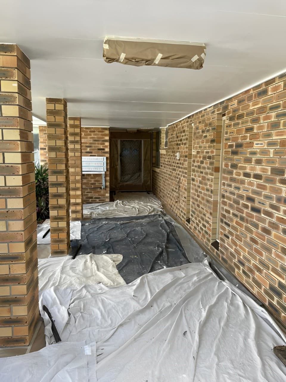 A Brick Wall Is Being Painted In A House — Tweed Heads Painting Service In Condong, NSW