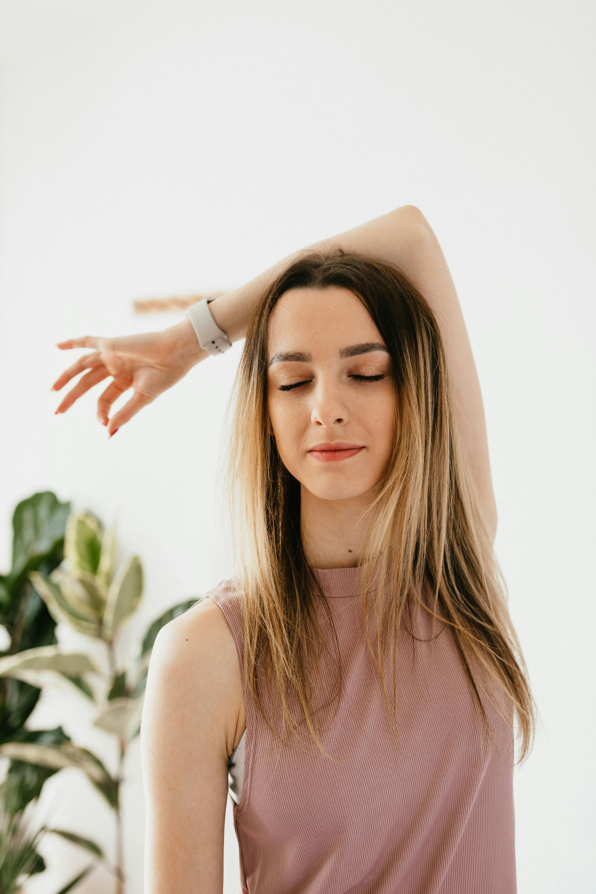 Une femme étire ses bras avec les yeux fermés.