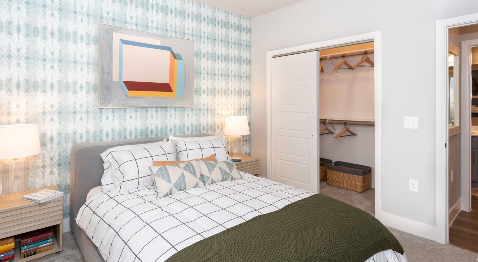 Bedroom with a made bed, two nightstands, lamps, and an open closet.