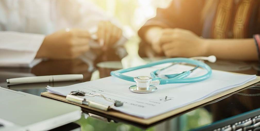 A stethoscope is sitting on top of a clipboard on a table.