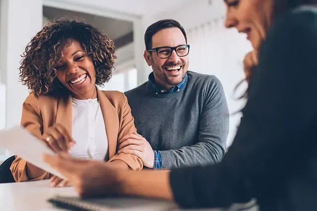 A man and a woman are sitting at a table talking to a woman.