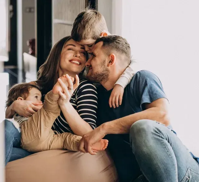 A family is sitting on a bean bag chair in front of a window.