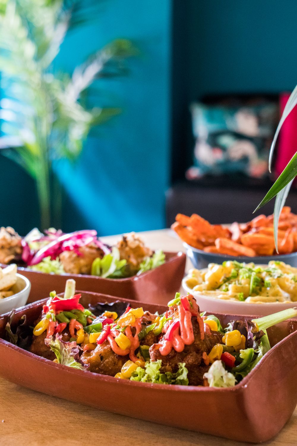 Close-up of a table with several dishes of food, including fried items, pasta, and sweet potato fries.