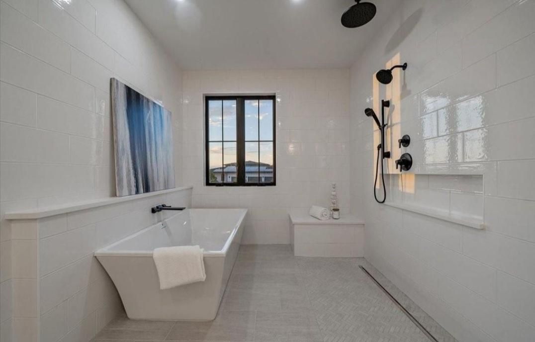 Modern white bathroom with walk-in tub, shower fixtures, and a window overlooking outdoors