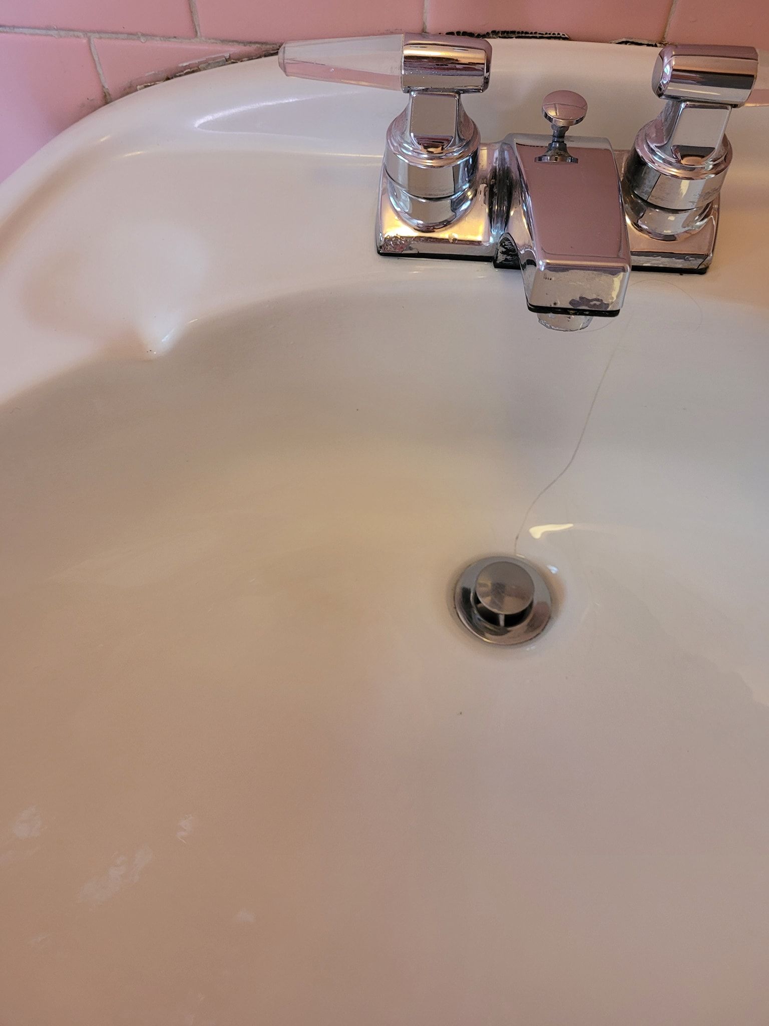 A bathroom sink with a chrome faucet and drain
