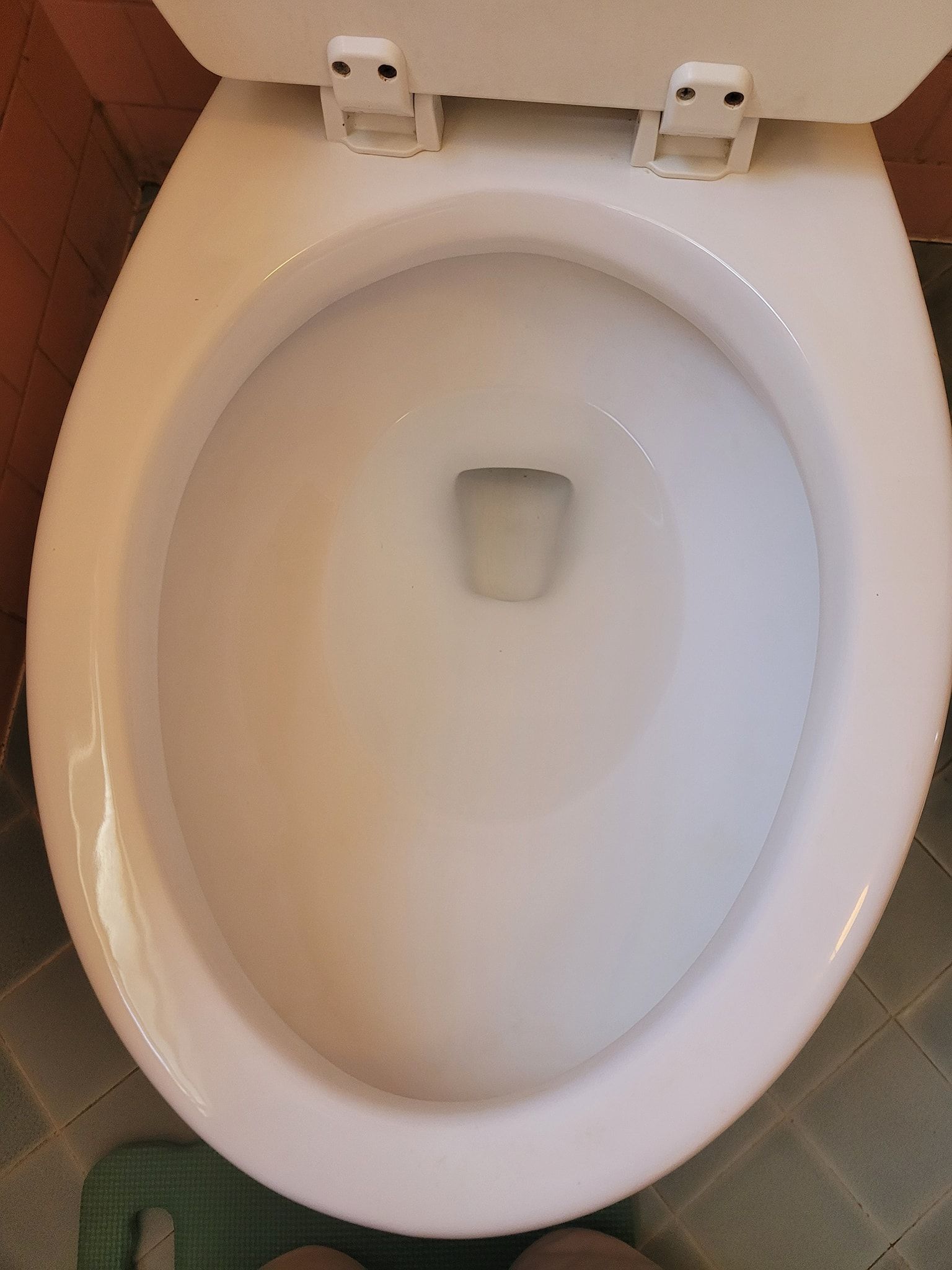 A white toilet is sitting on a tiled floor in a bathroom.