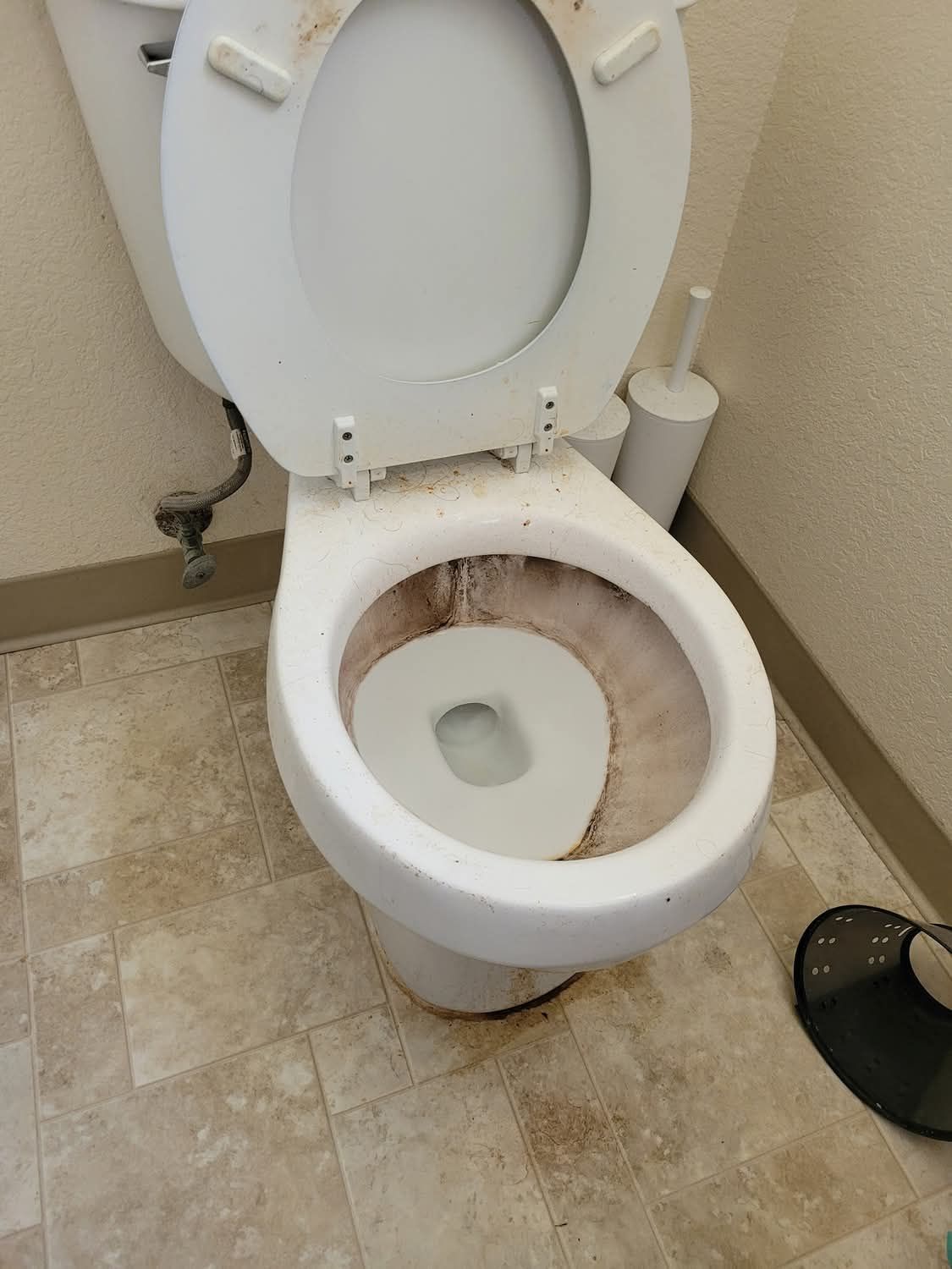 A toilet in a bathroom with the lid up