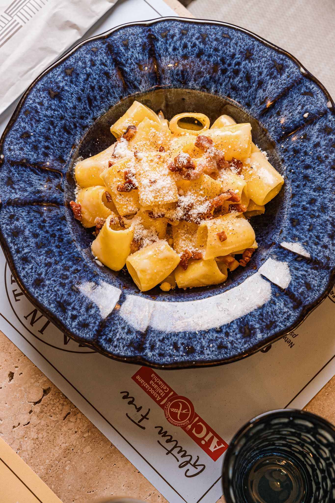 Un primo piano di un piatto di pasta con sugo e formaggio su un tavolo.