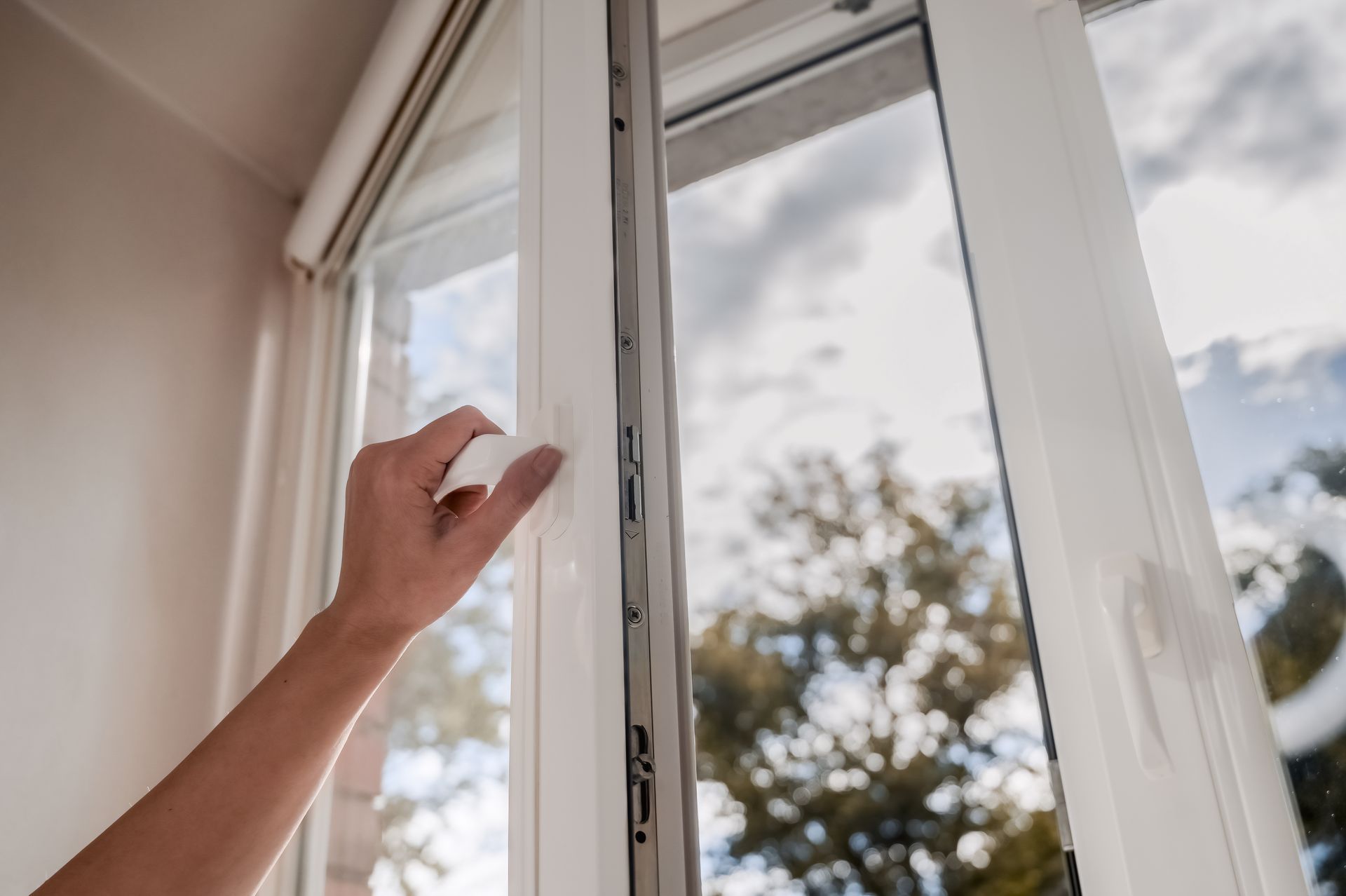 A hand opens a vinyl window on a blue sky background. A hand opens a vinyl window on a blue sky background.