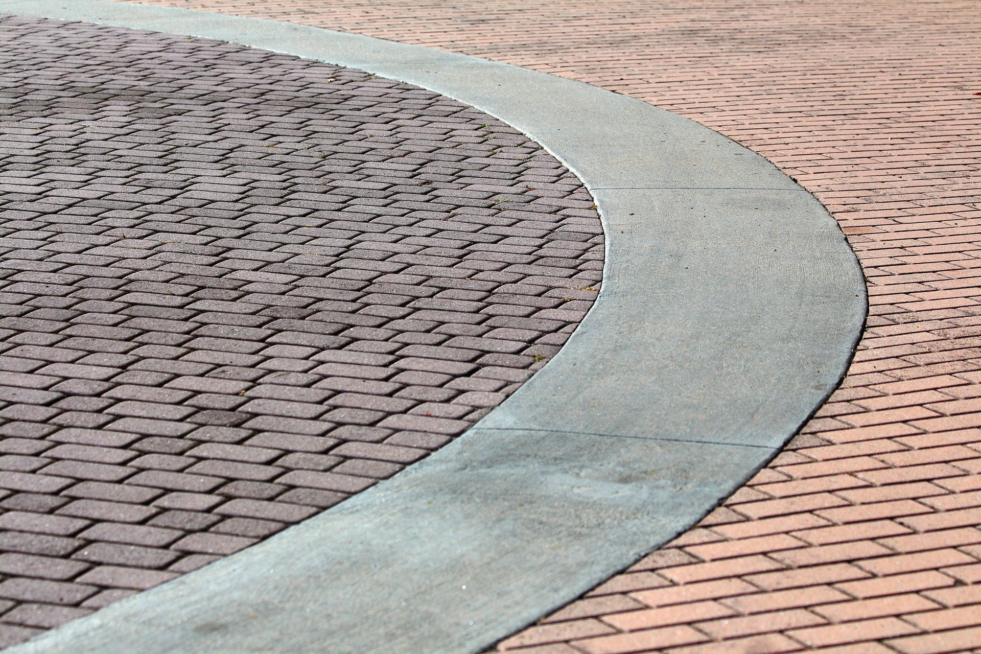 A brick walkway with a green curb and a circle in the middle