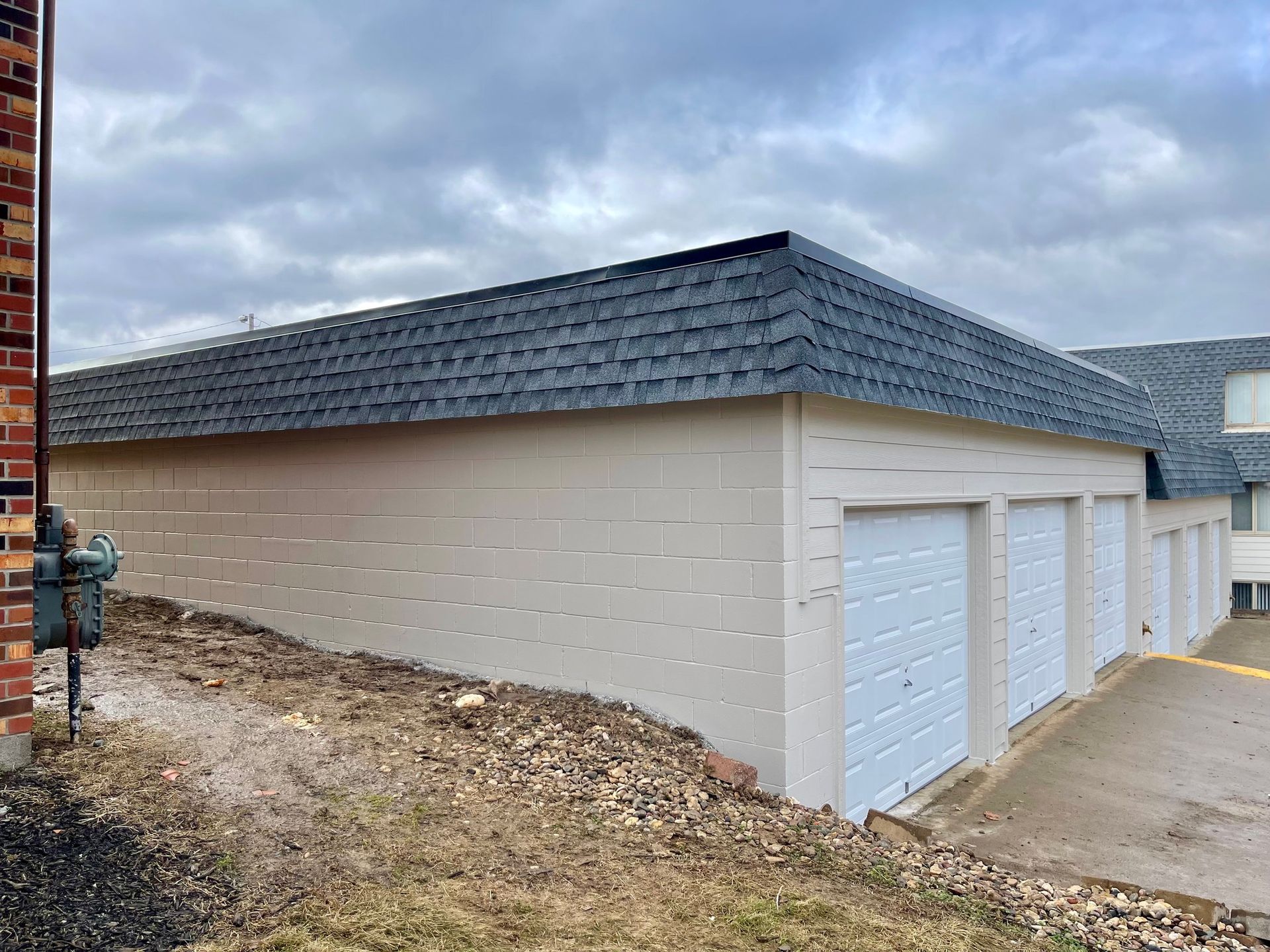 A row of white garage doors with a brick building in the background  | Fire Restoration  Projects | Siefken Roofing and Remodeling Services in Omaha, NE