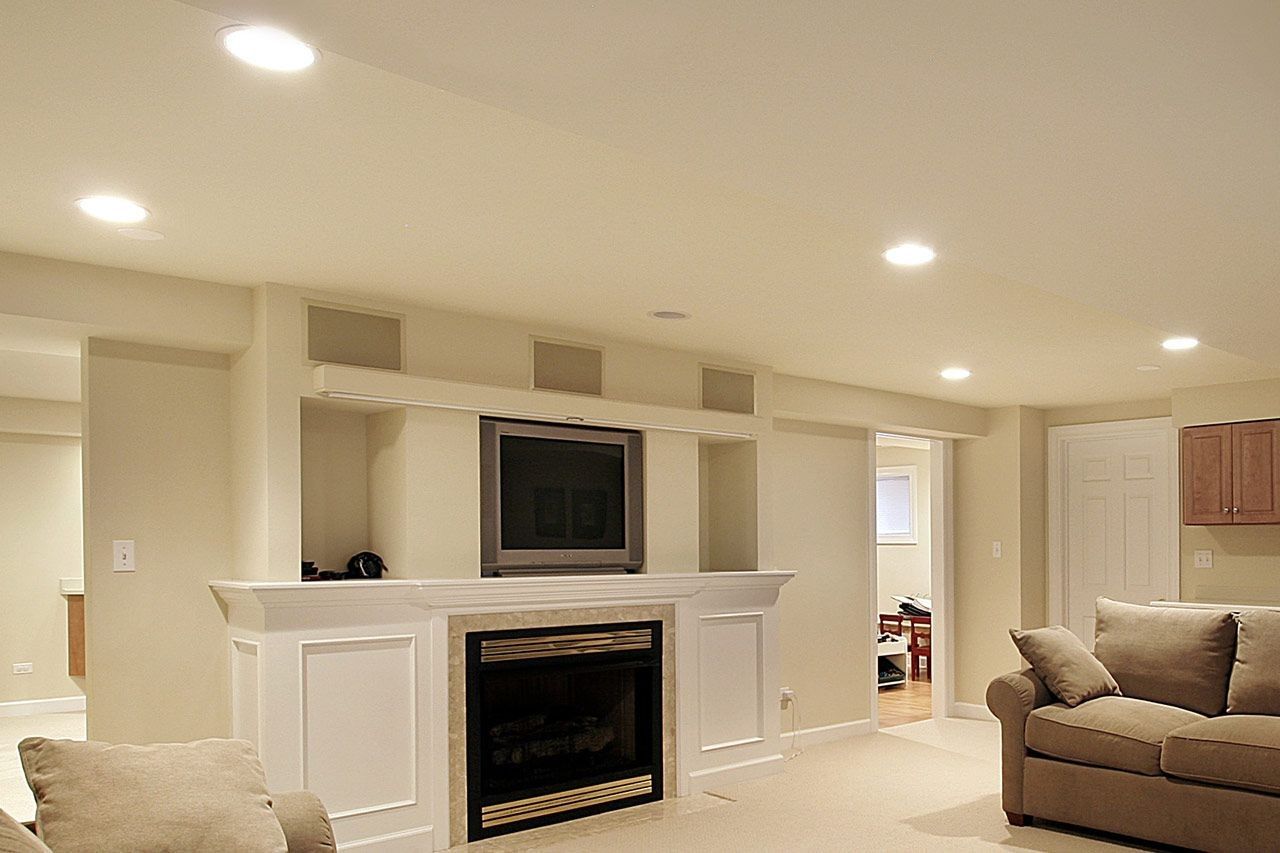 Living room with fireplace, TV, and couches. Neutral tones, recessed lighting.