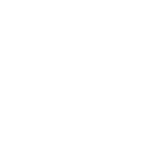 A glass of beer with a dense, white foam head sits on a dark wooden table in a dimly lit bar.