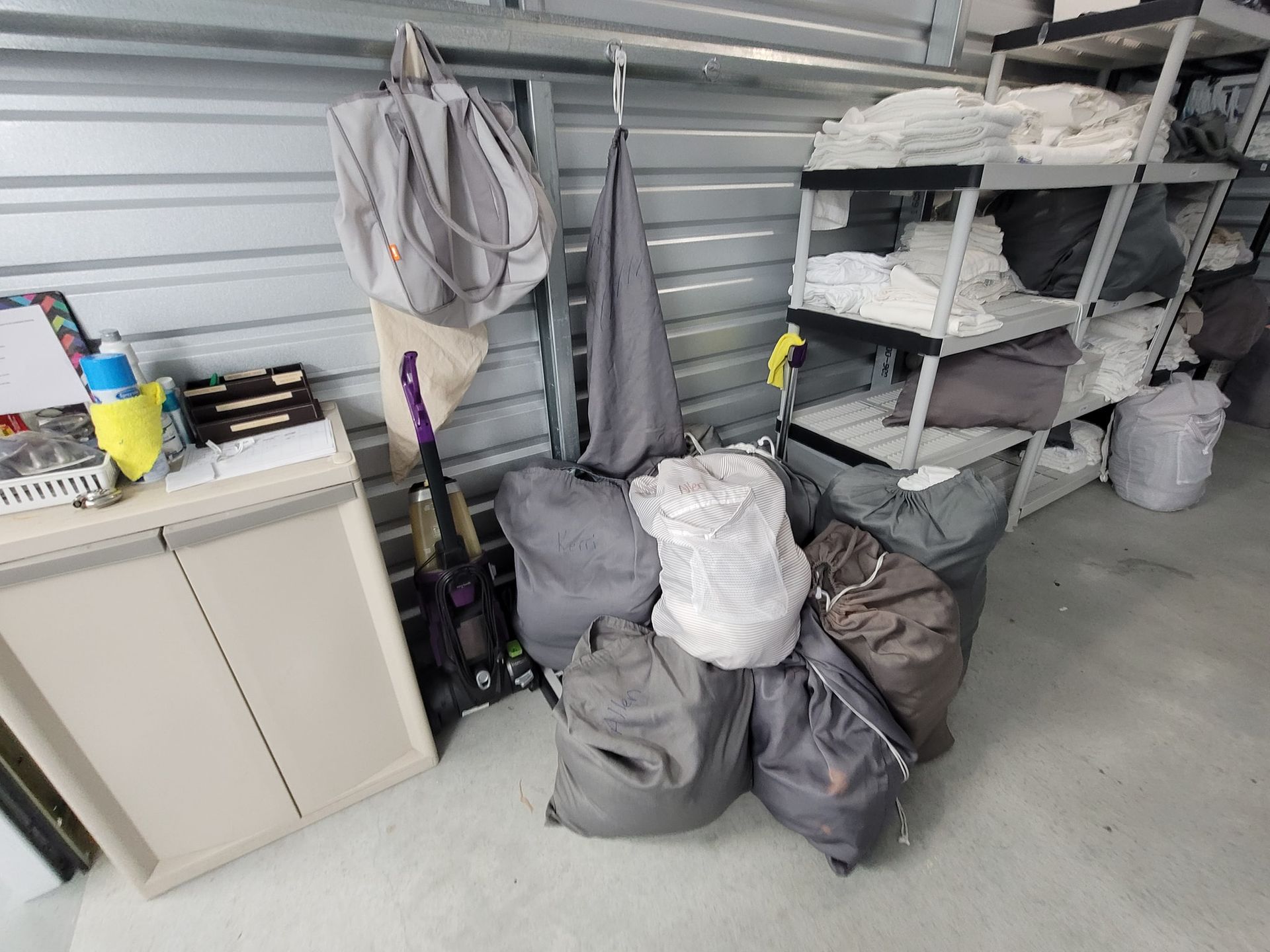 Storage unit with bags, shelving, and a small cabinet. Grey and white items.
