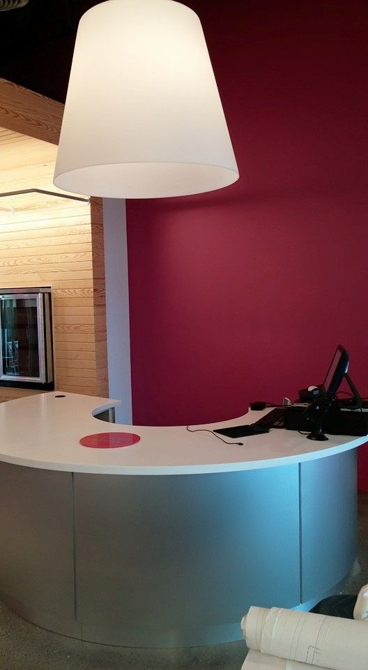 Reception desk with a white countertop, a large lamp, and a pink wall.