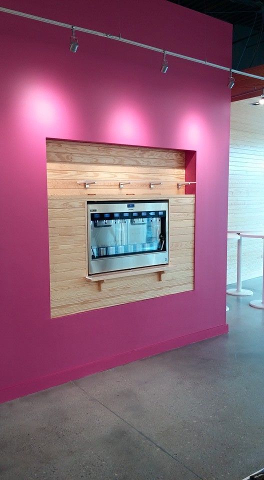 Pink wall with a wooden inset housing a stainless steel appliance.