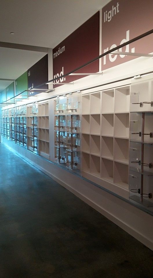 White shelves with clear glass displays line a long hallway. Color-coded signs read 