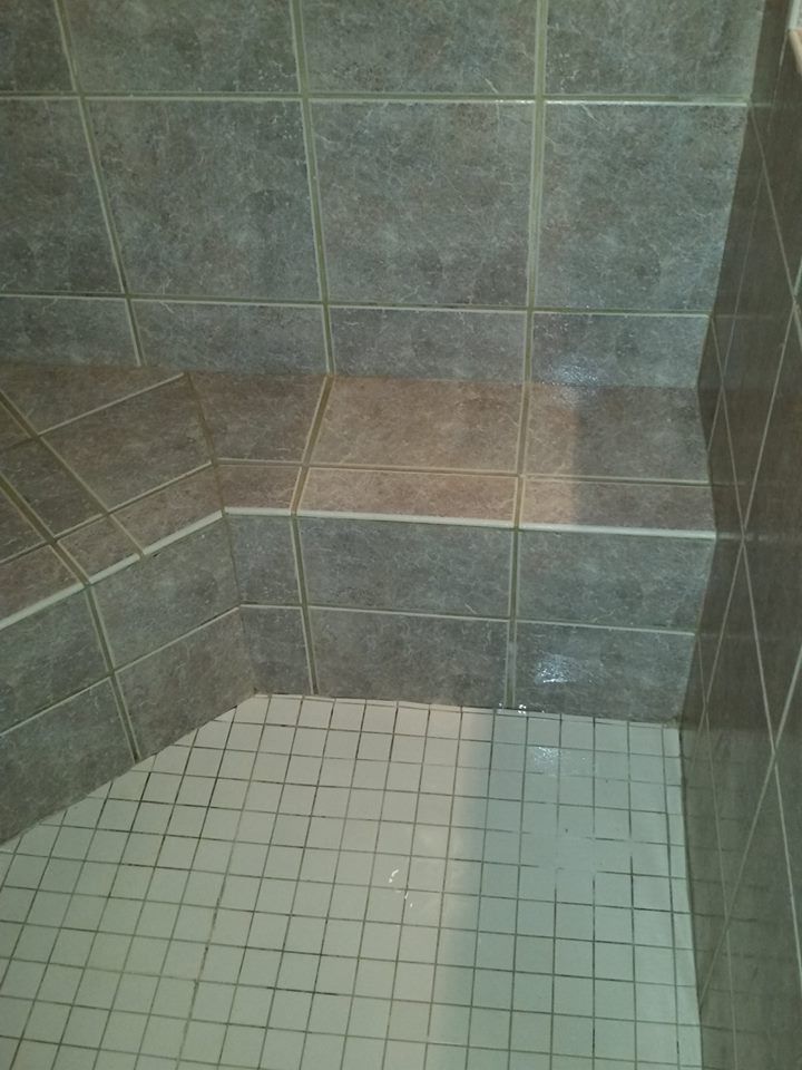 Gray tiled shower with a built-in seat, tiles on the floor and walls.