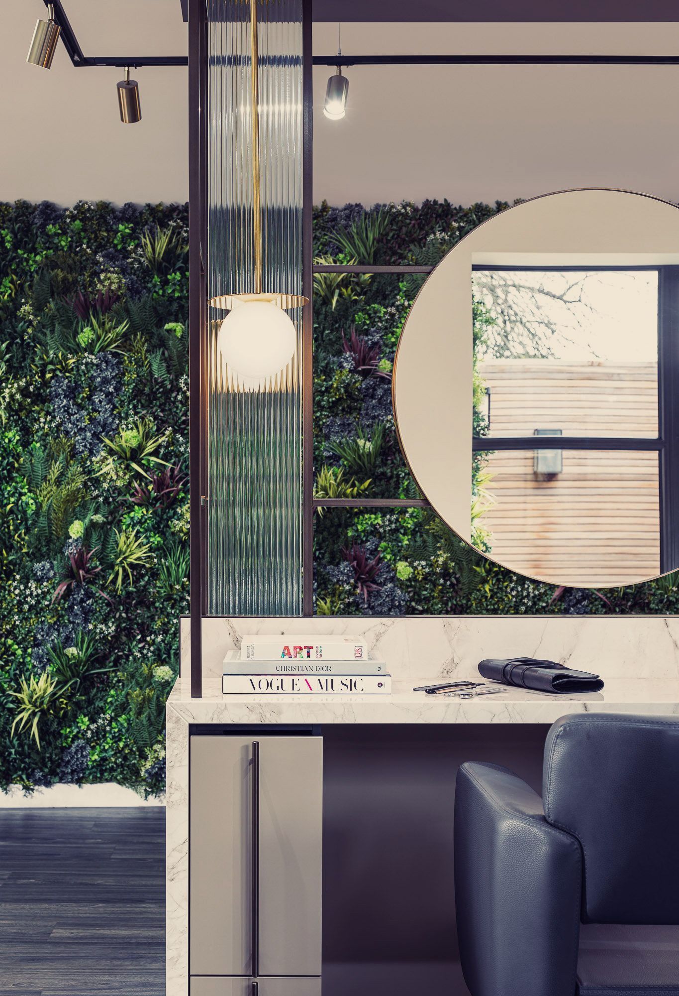 A hair salon with a green wall and a round mirror.