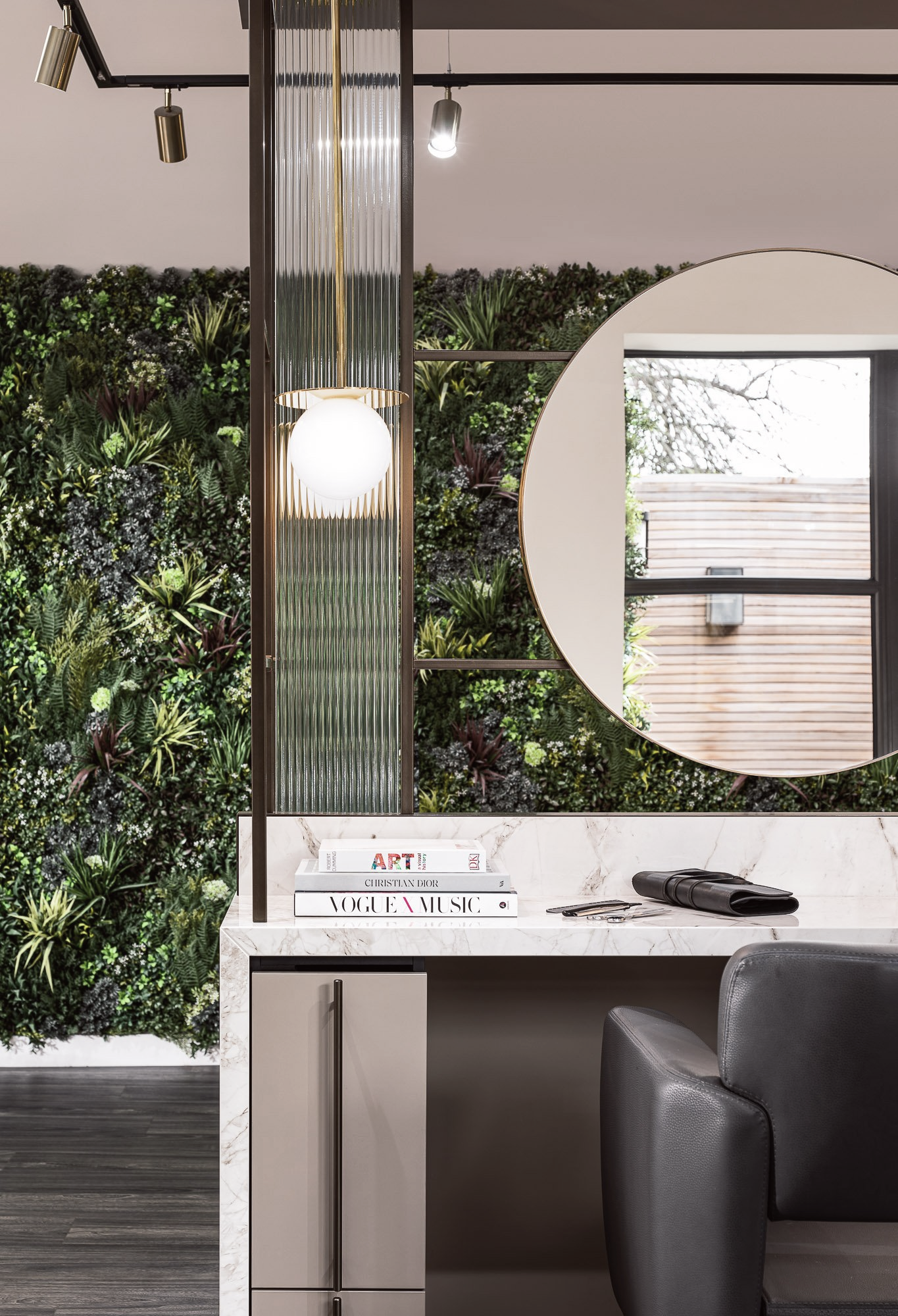 Leo Bancroft Modern minimalist living room with a large round mirror, pendant light, and gray chair beside a desk.