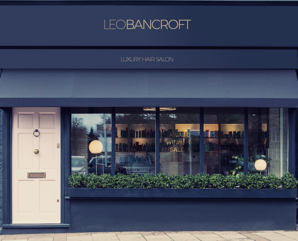 The front of a store with a pink door and a black awning.