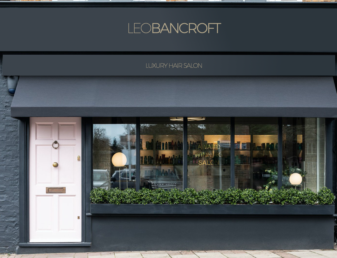 A store front with a black awning and a pink door