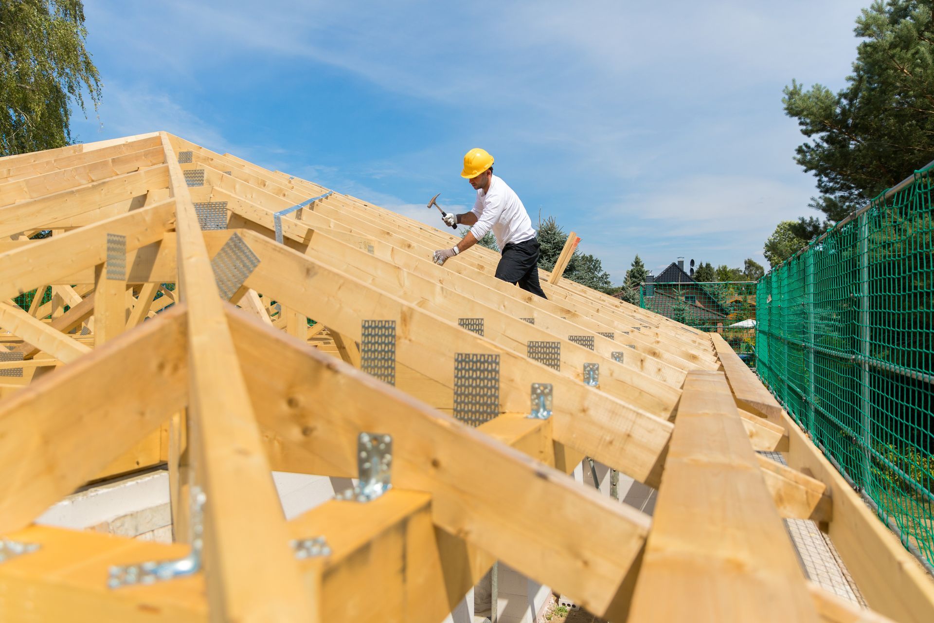A man is working on the roof of a house under construction