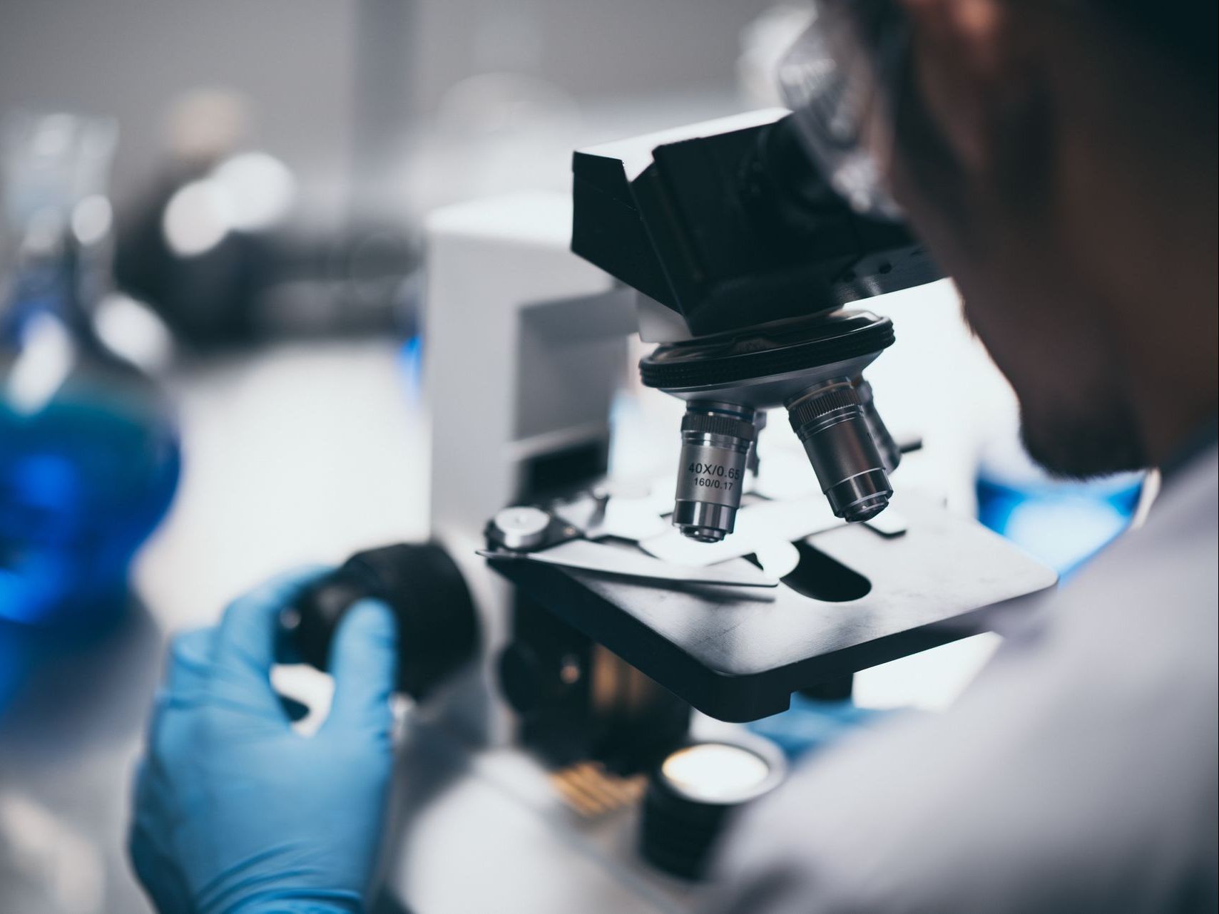 A man is looking through a microscope in a laboratory.