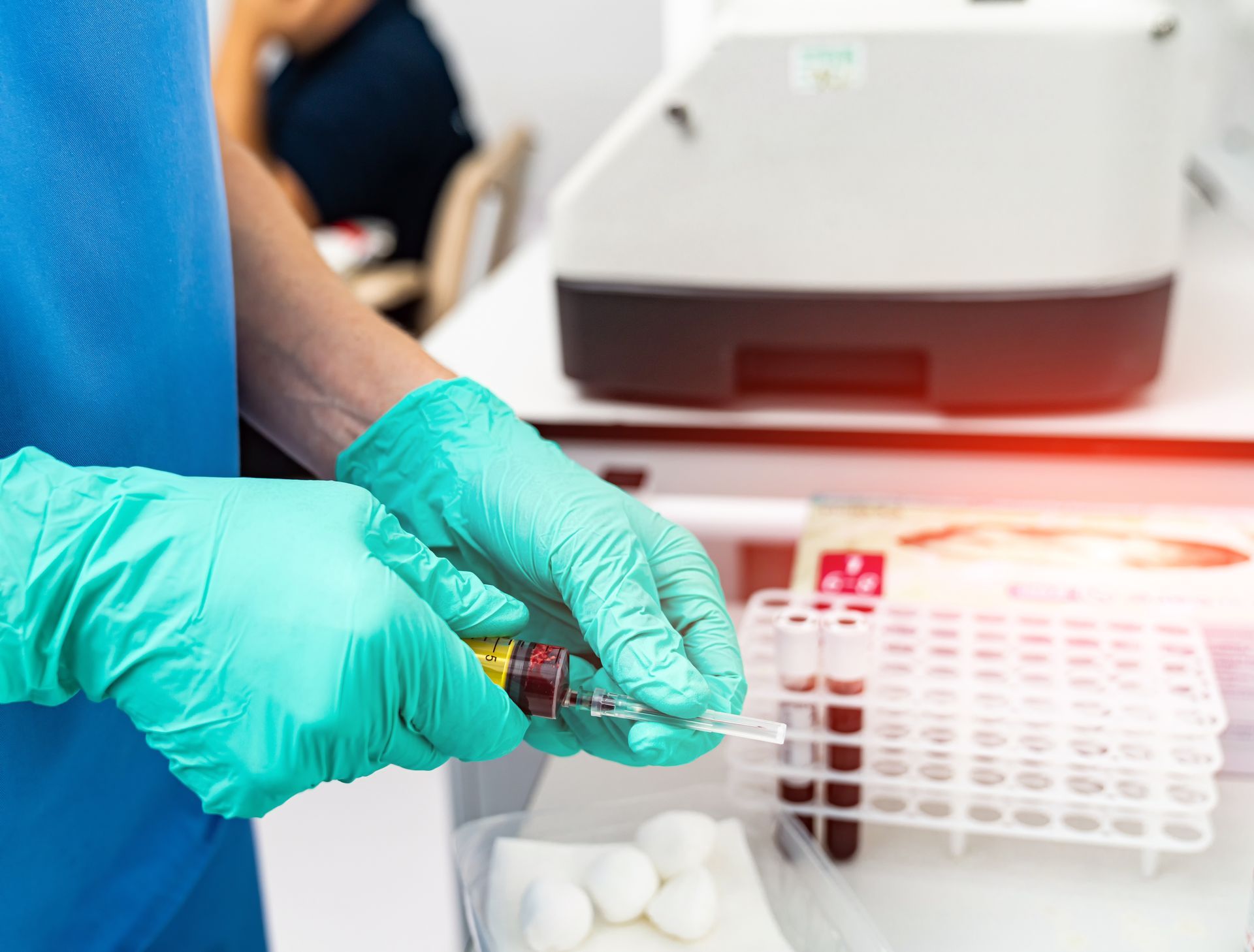 A person wearing green gloves is holding a syringe in a laboratory.