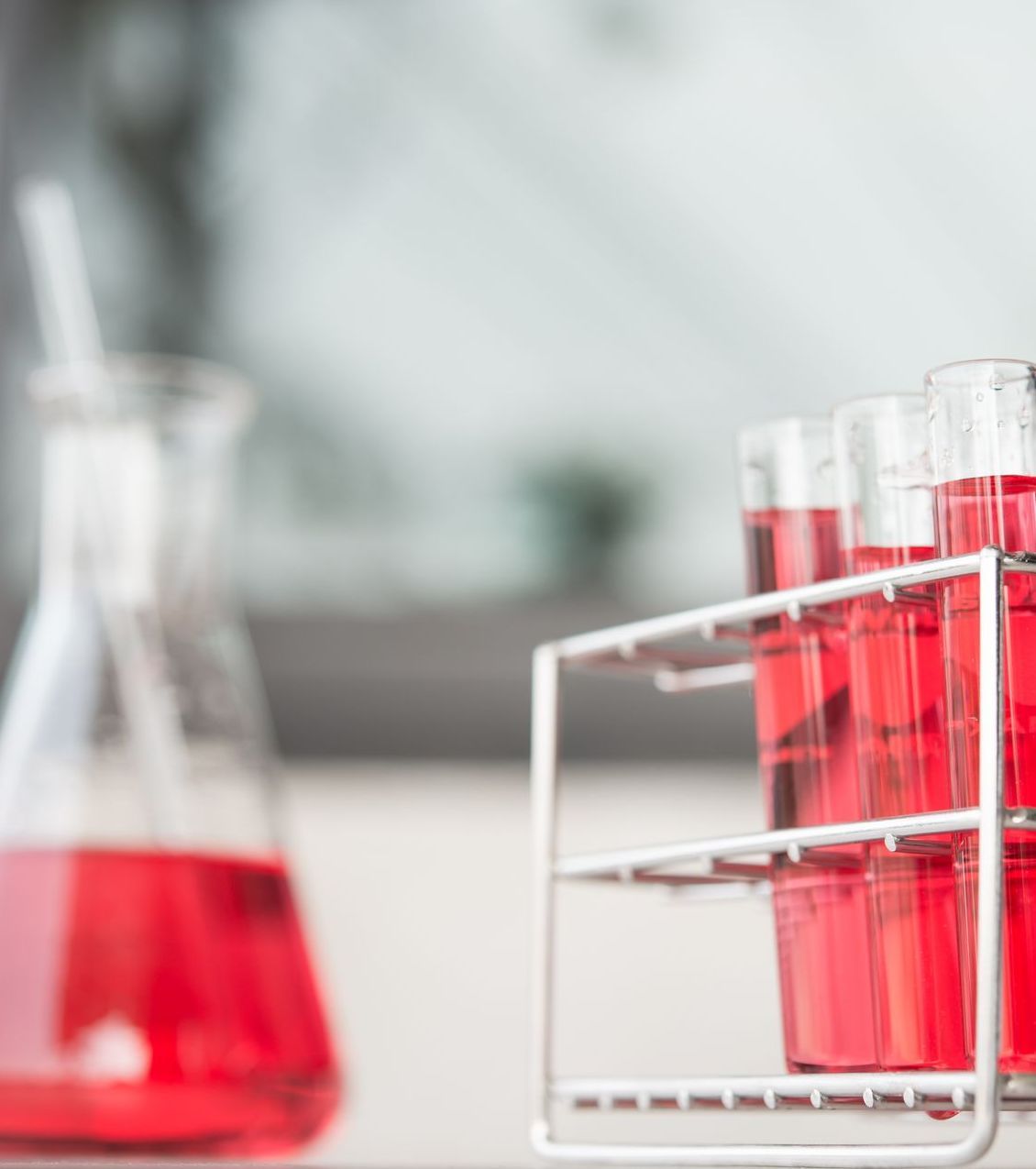 A bunch of test tubes filled with red liquid are sitting on a table.