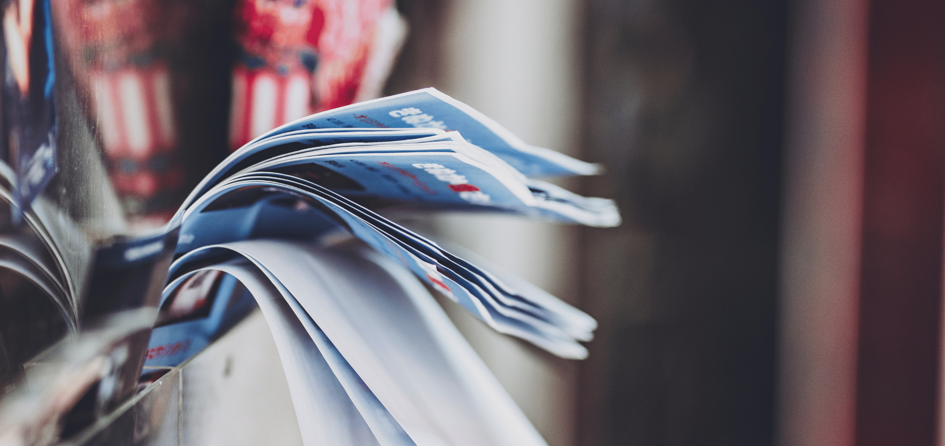 A person is holding a stack of newspapers in their hand.