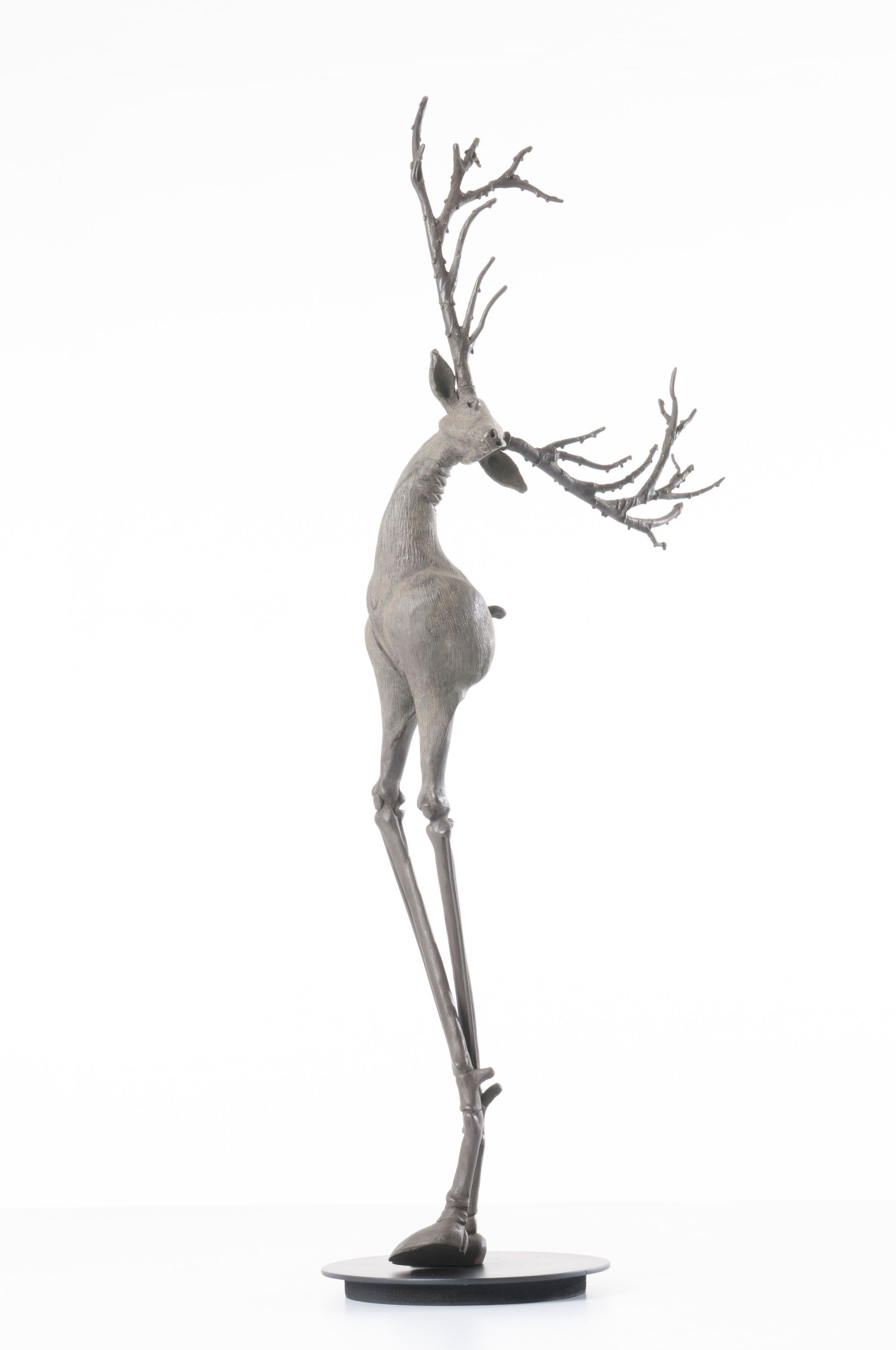 A statue of a deer with long legs on a white background.