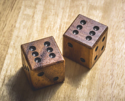 Two wooden dice are sitting on a wooden table.