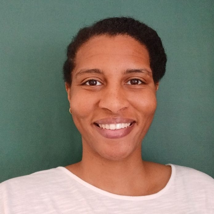 Smiling woman with dark skin, wearing a white top, in front of a green background.