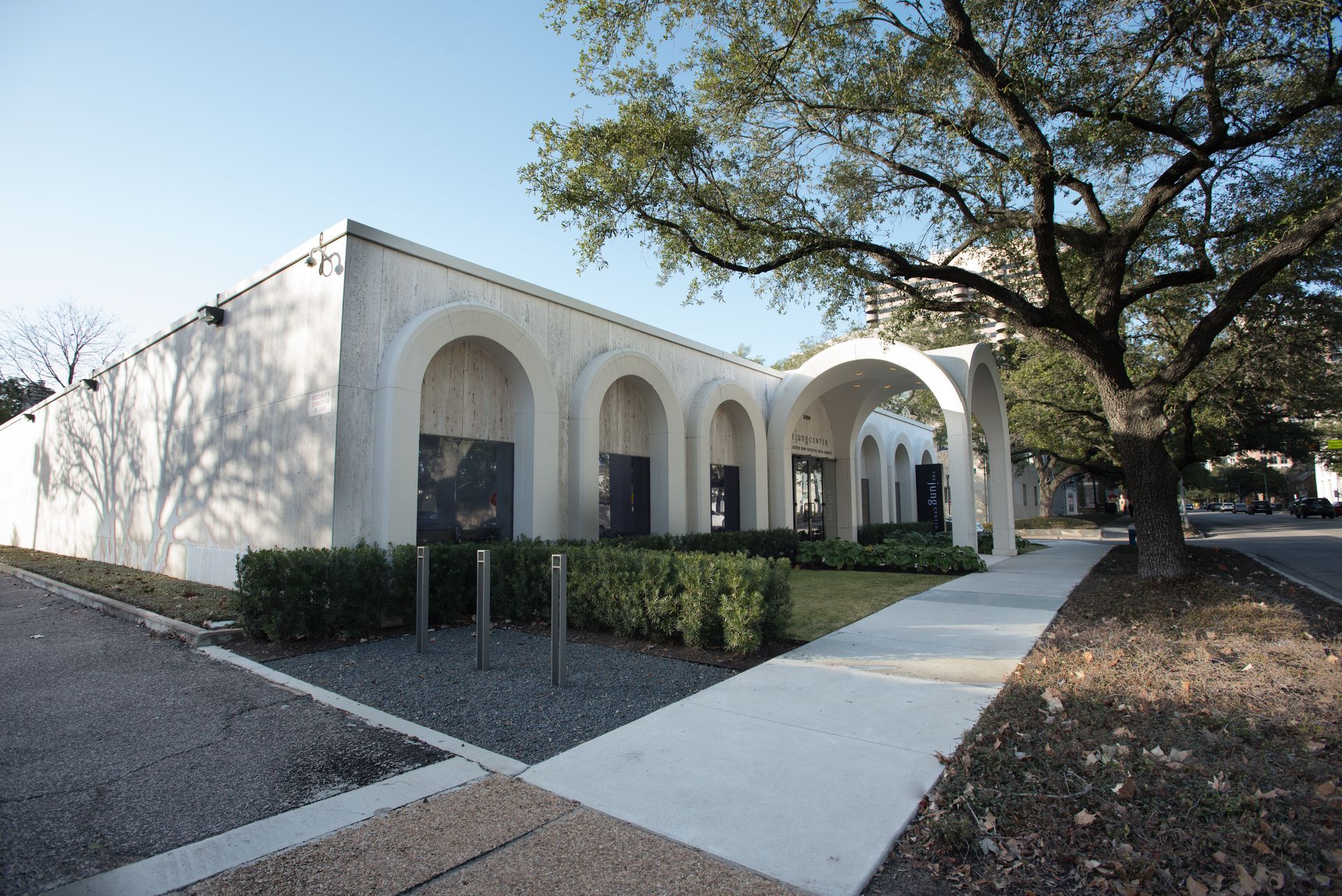 A white building with arches and a tree in front of it