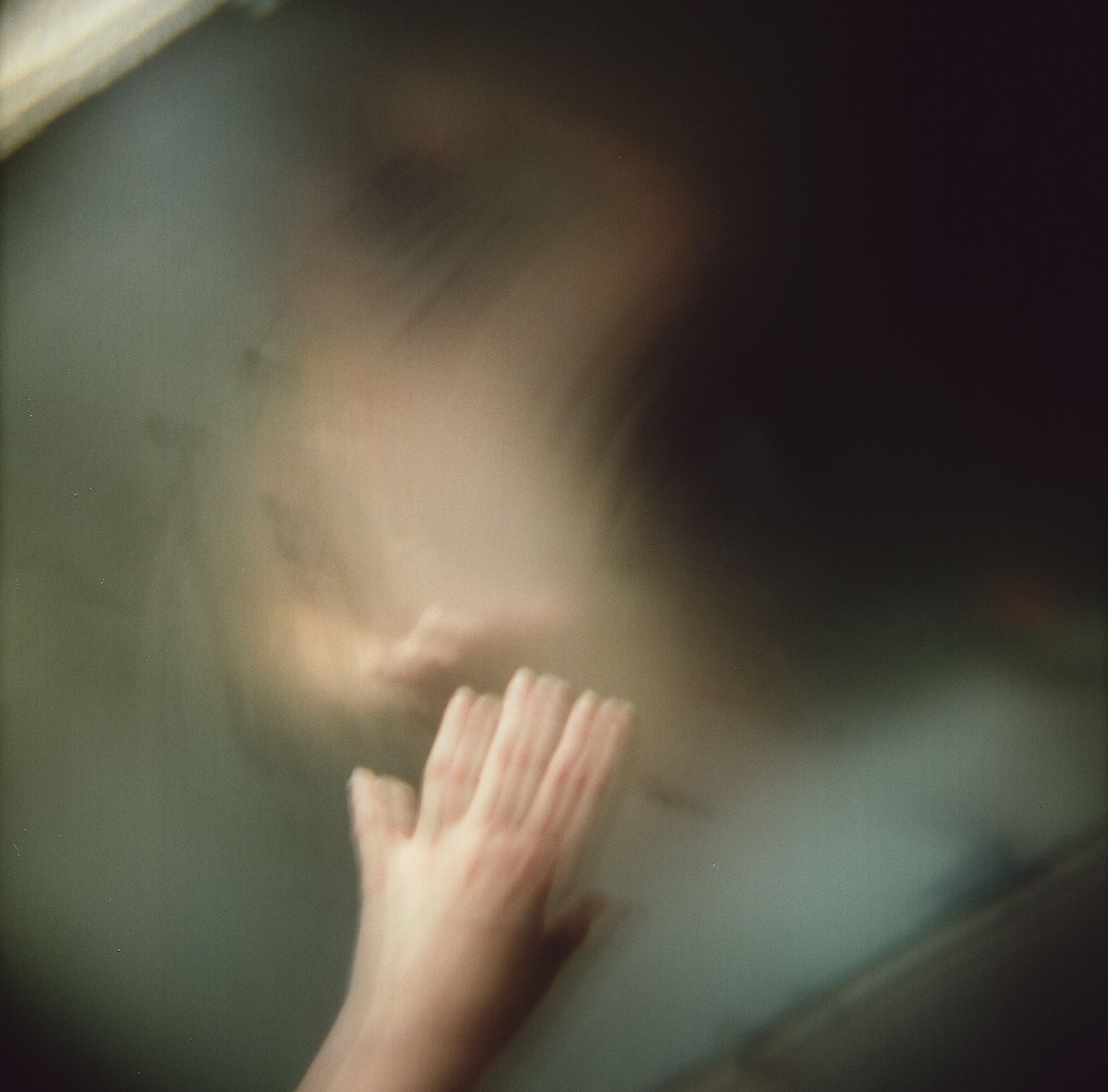 A blurry picture of a person 's hand touching a glass door.